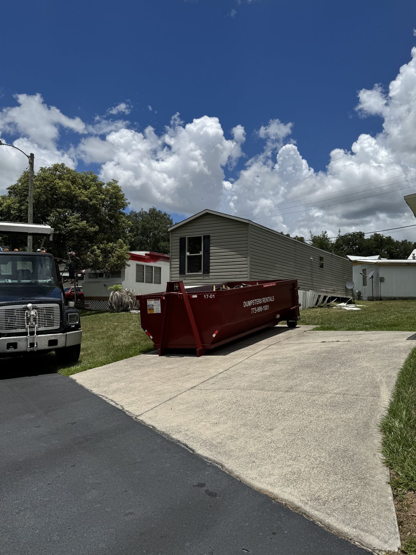 DumpsterX roll-off truck delivering a maroon dumpster in the Zephyrhills FL area